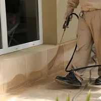 General pest control technician spraying exterior perimeter around a home in Boston, MA